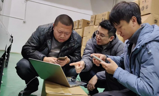 圖為卷煙物流配送中心主要領(lǐng)導同裝備信息小組自主調(diào)試設(shè)備