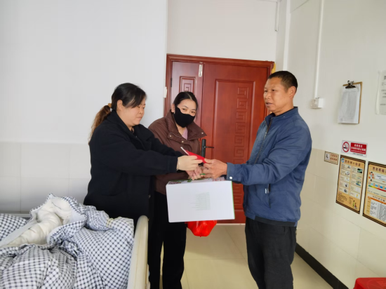 圖為定南縣煙草專賣局駐村隊(duì)員黃文平看望患者李紹輝
