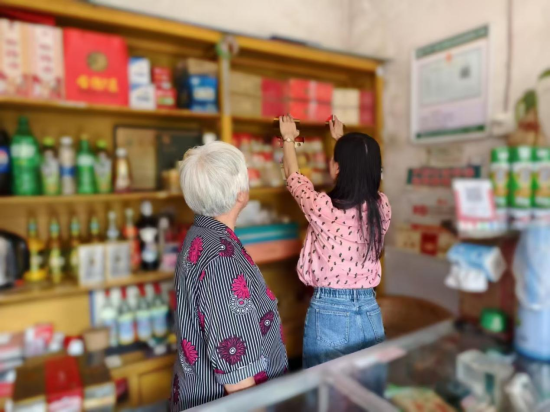 圖為客戶經(jīng)理幫助老人美化店鋪