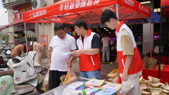 圖為普法志愿者發(fā)放法律宣傳海報.孫淑玲 攝